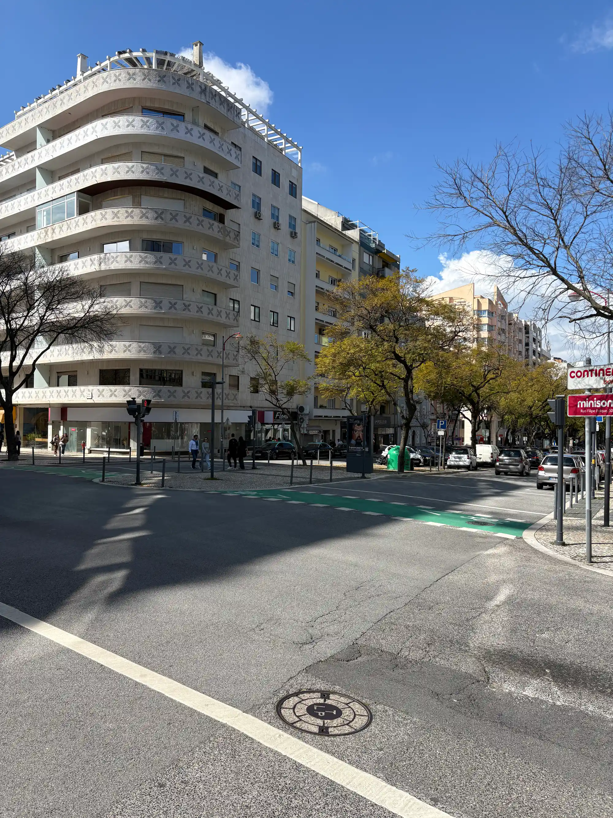 Modern curved apartment building on a sunny street in Avenidas Novas, Lisbon, Portugal.