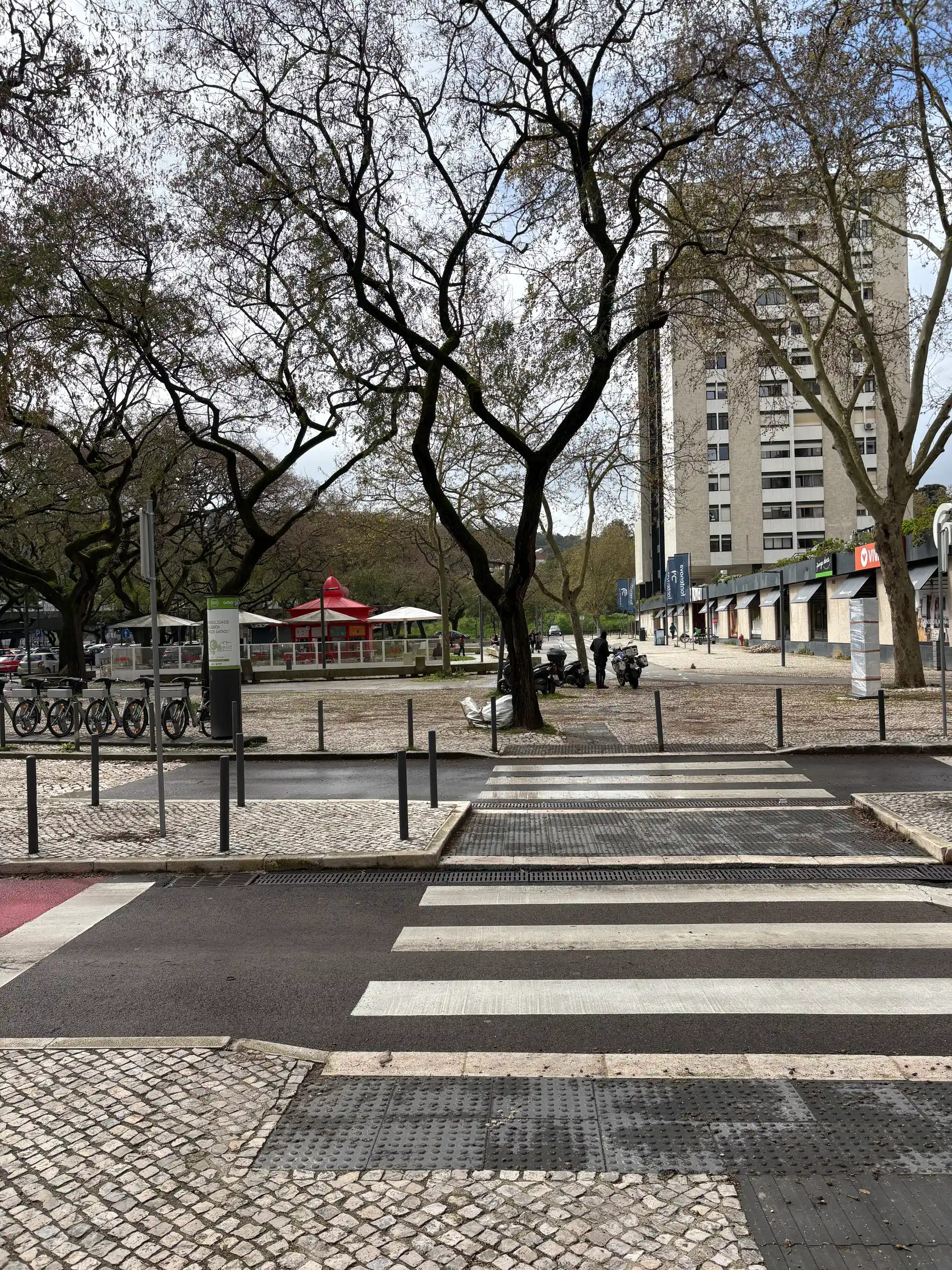 Benfica Lisbon urban street with pedestrian crossing, trees, bike parking, and local park area