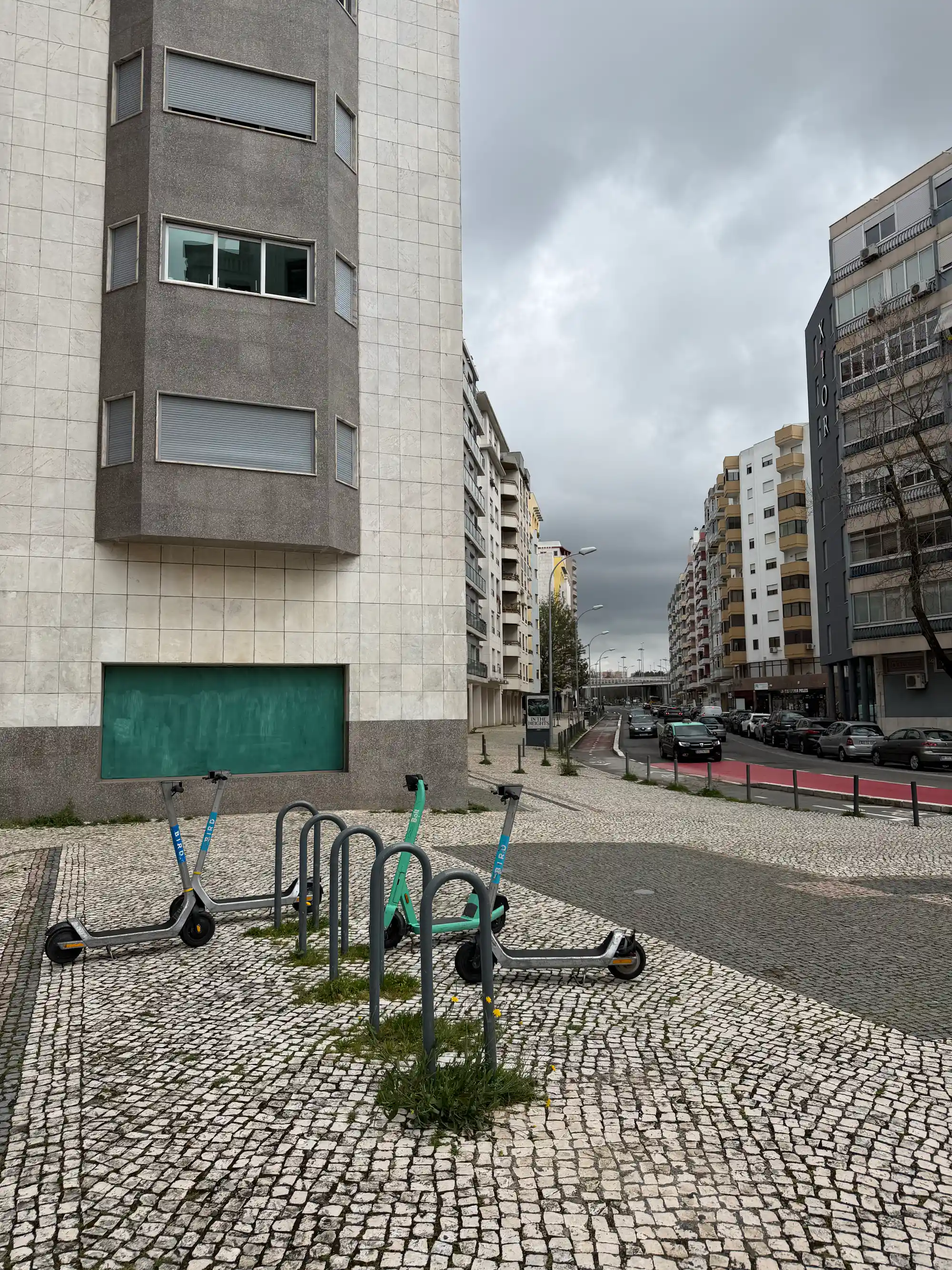 Benfica Lisbon residential street with apartment buildings, parked cars, and shared electric scooters in urban setting