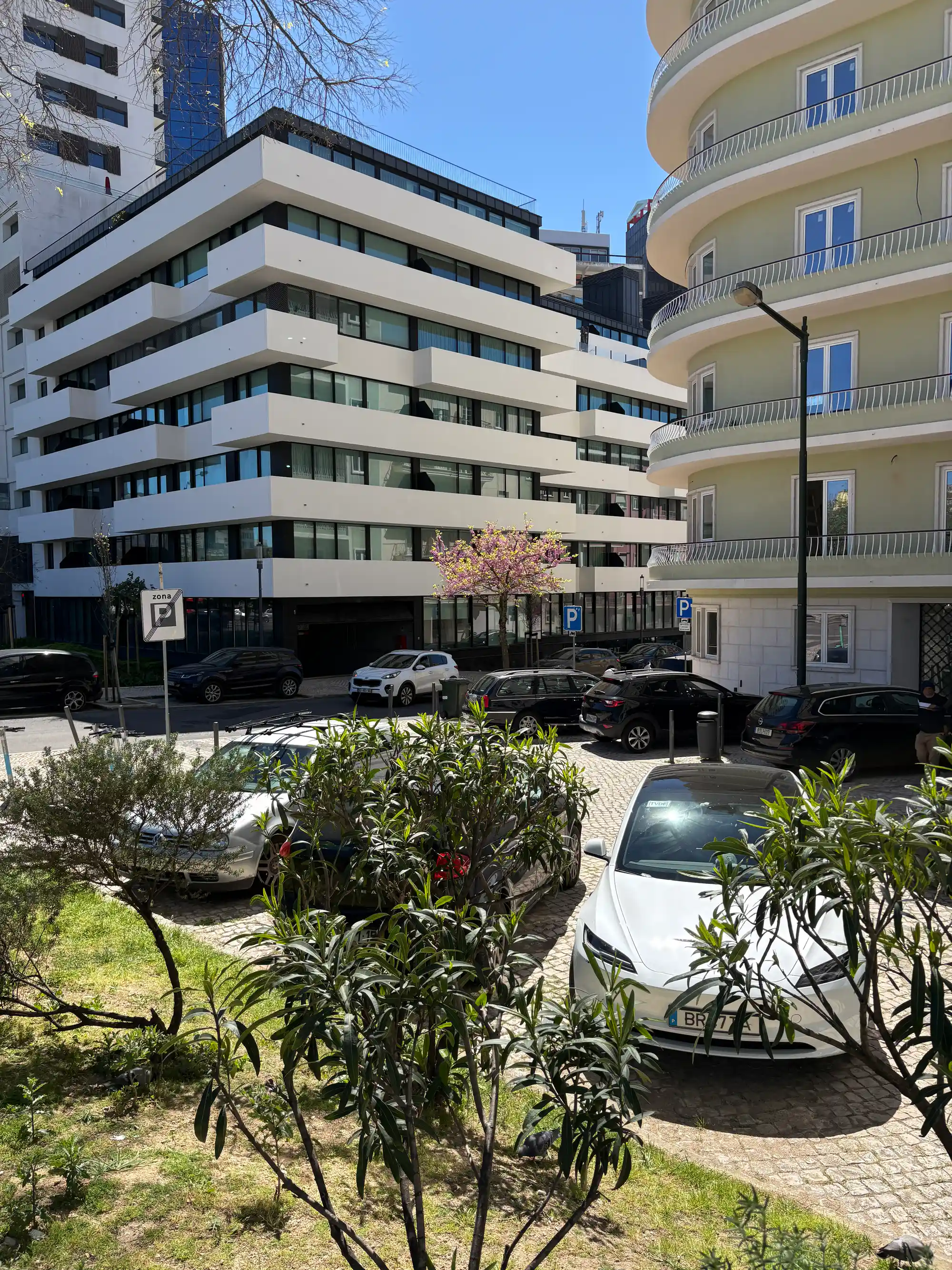 Жилой комплекс Campolide Lisbon – современные здания с балконами, припаркованными автомобилями, зеленью и солнечной городской атмосферой.