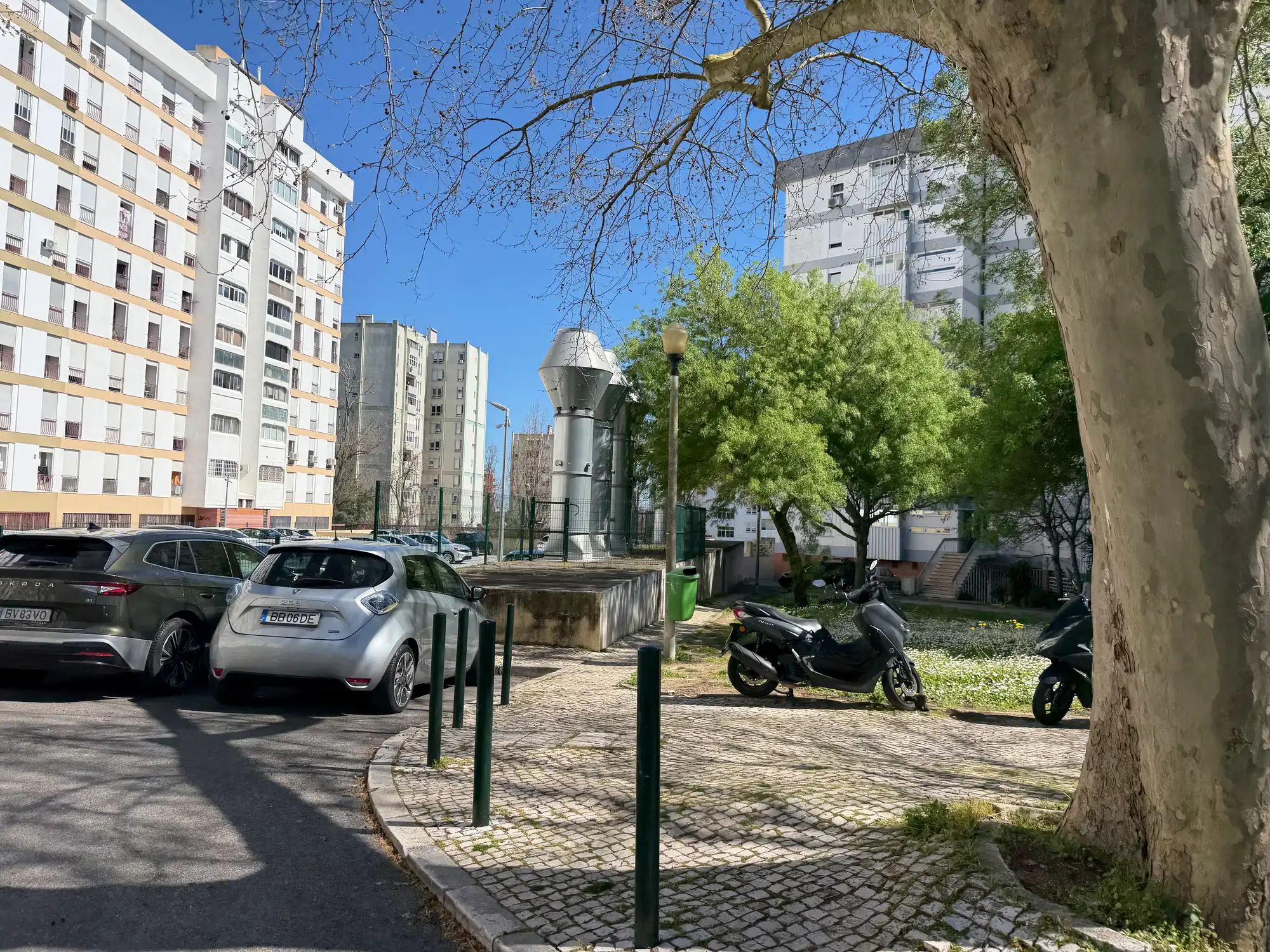 Olivais é uma área residencial de Lisboa com prédios de apartamentos, carros estacionados, árvores e calçada para pedestres.