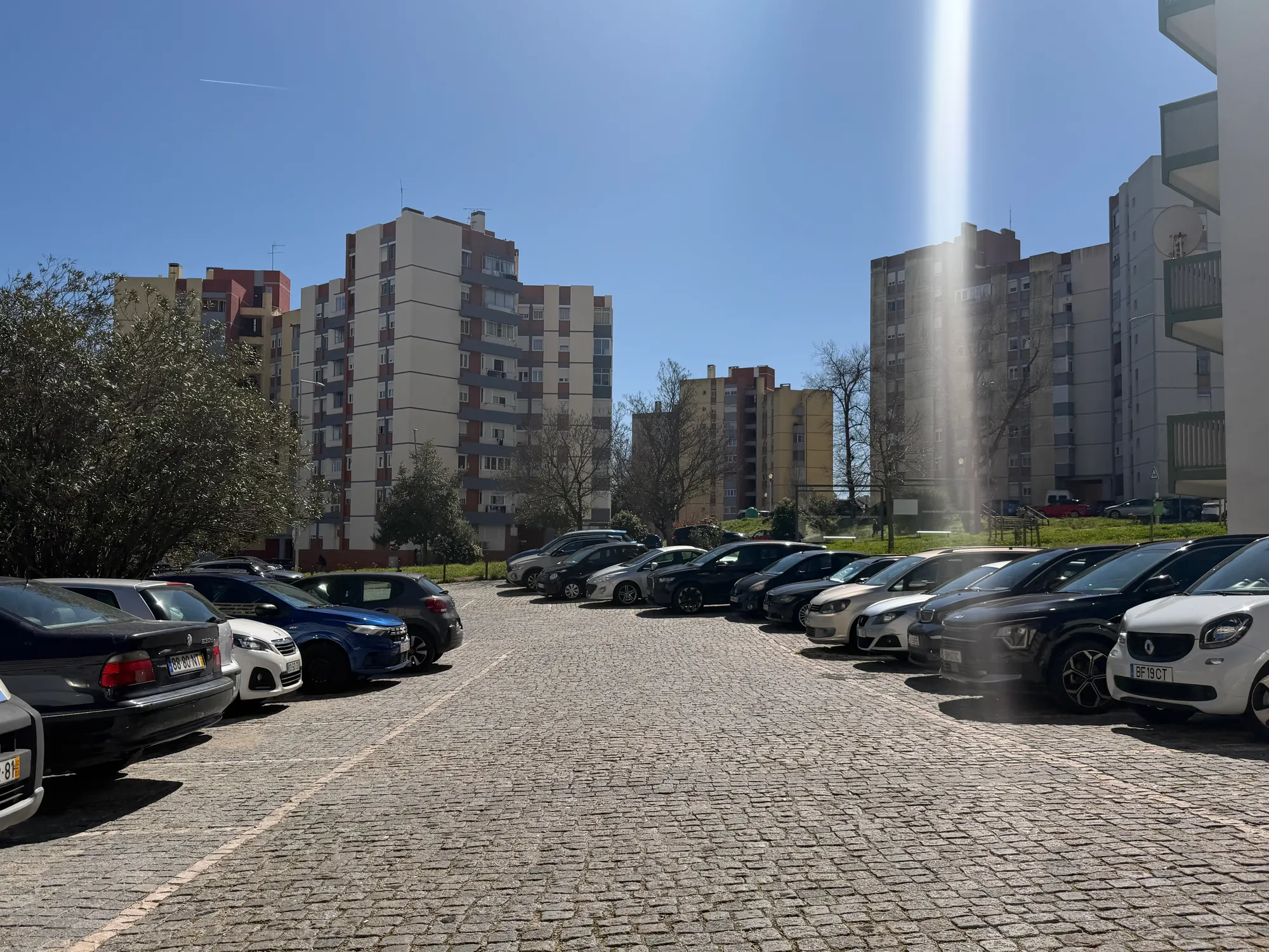 Olivais Lisbon apartment buildings with parking area, cars, and sunny urban residential environment
