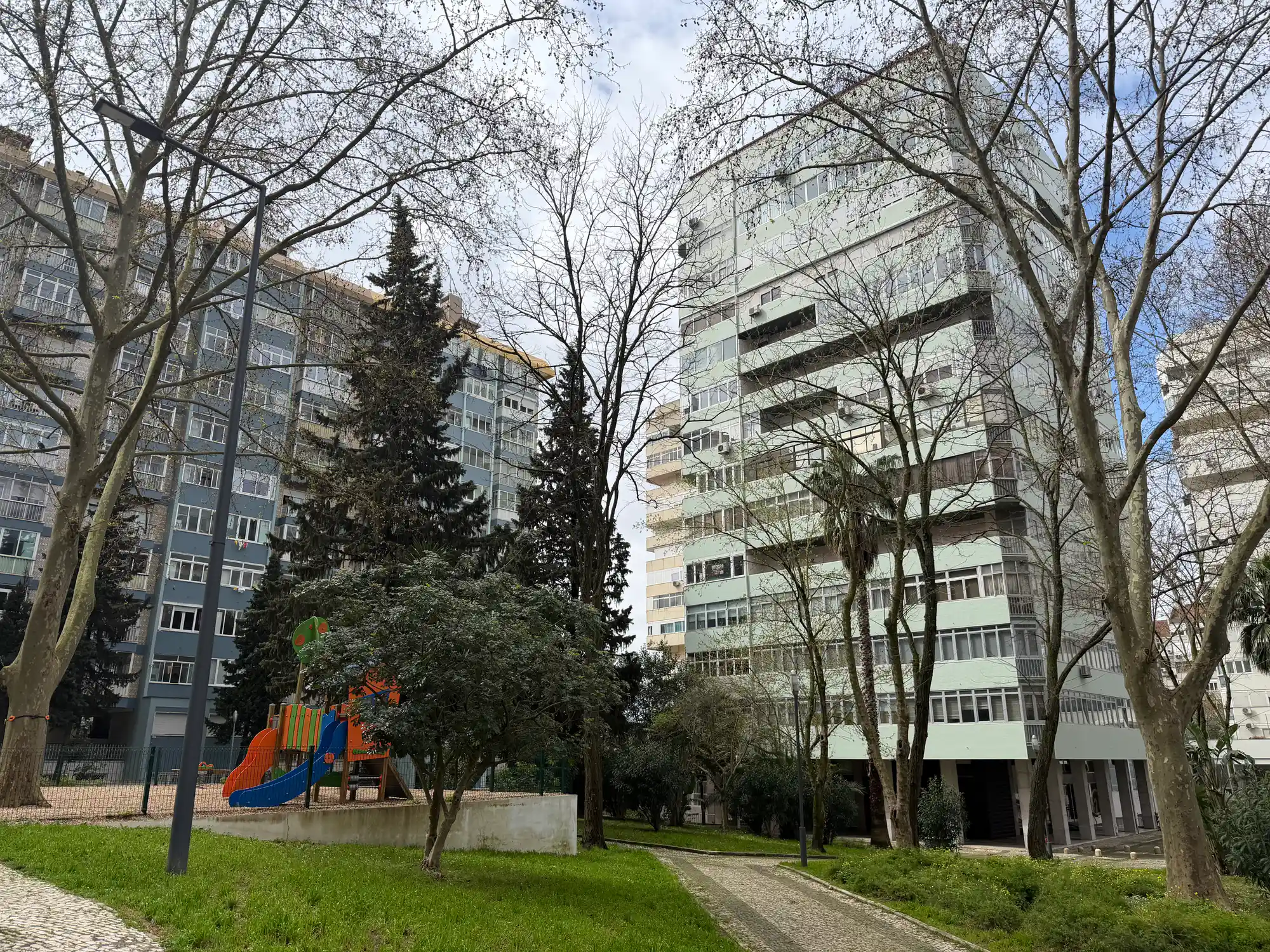 São Domingos de Benfica, Lisbon residential area with apartment buildings, playground, trees, and green space.