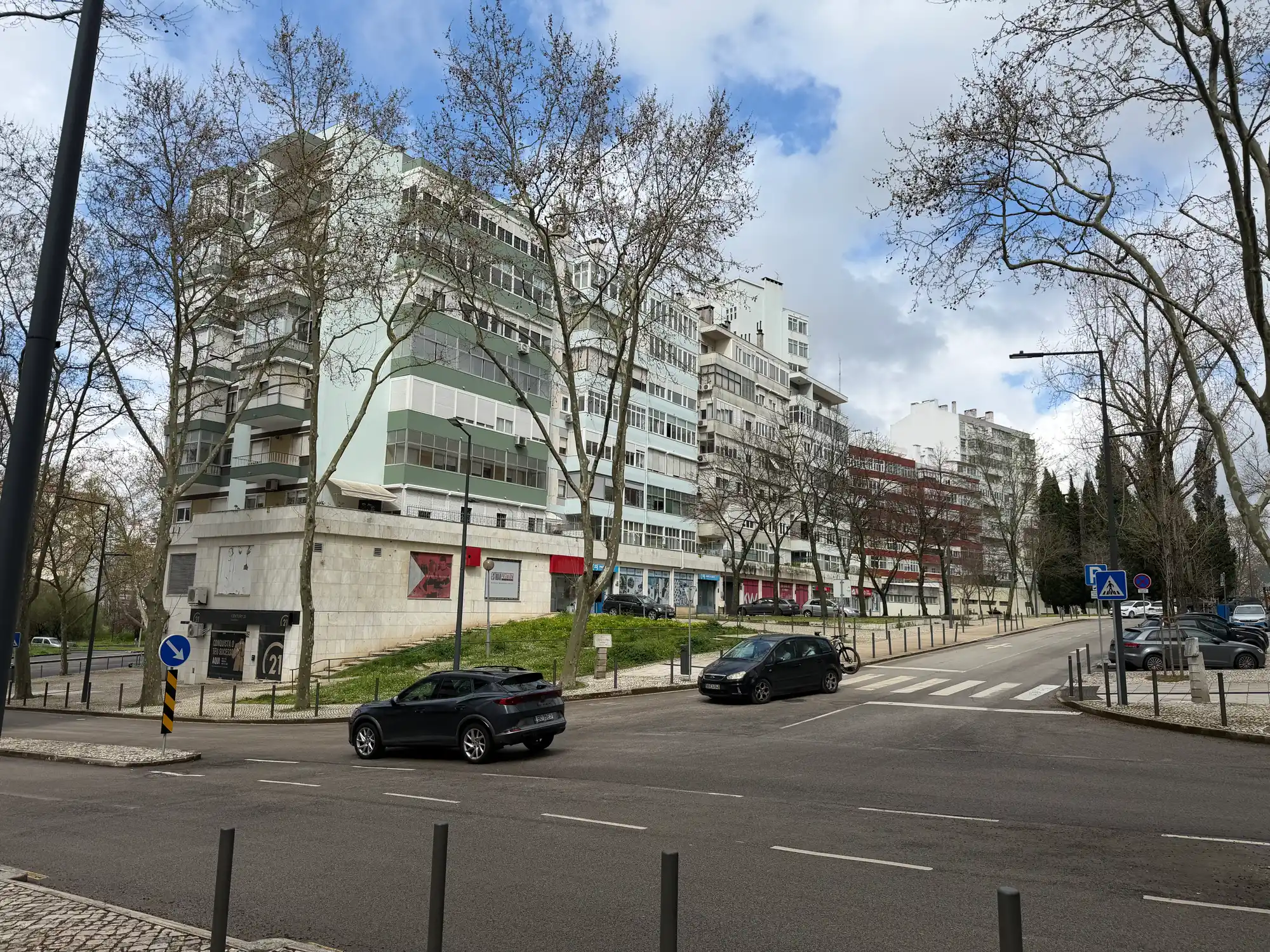 São Domingos de Benfica, Lisbon, is a residential street with apartment buildings, trees, and urban traffic.