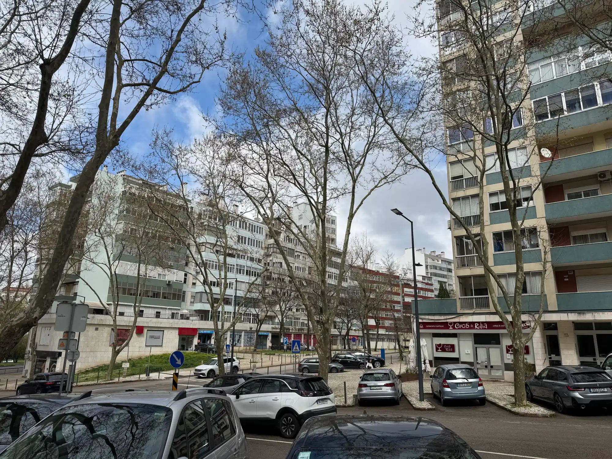 São Domingos de Benfica, Lisbon, is a residential area with apartment buildings, parked cars, trees, and local shops.